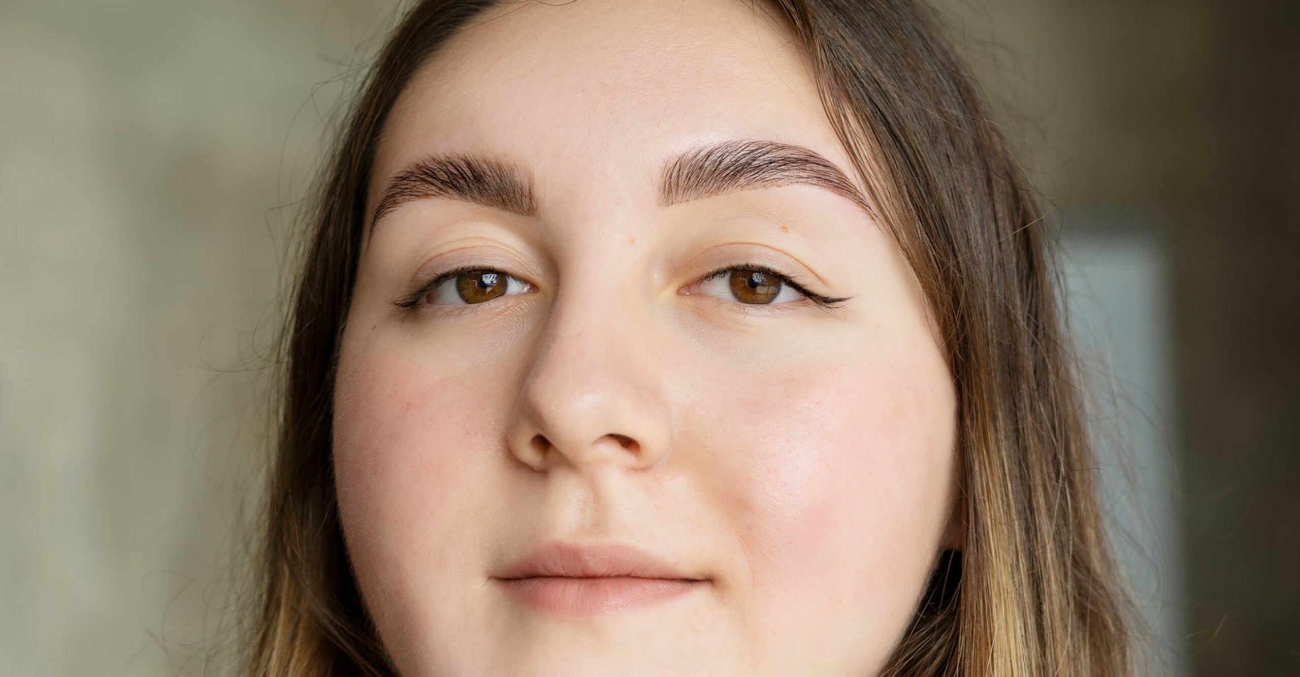 close up on person’s face with laminated brows, long eyelashes, and brunette hair